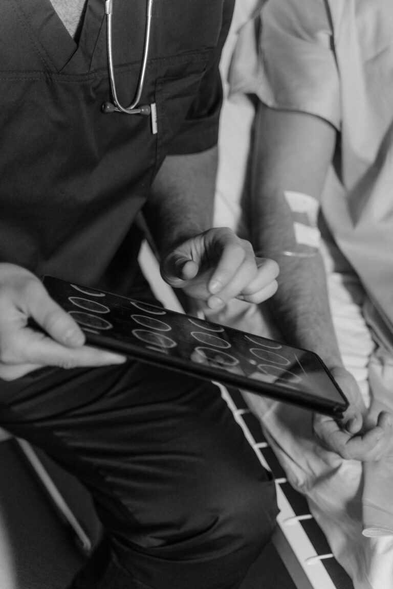 A doctor uses a tablet to show a CT scan to a patient in a hospital setting.